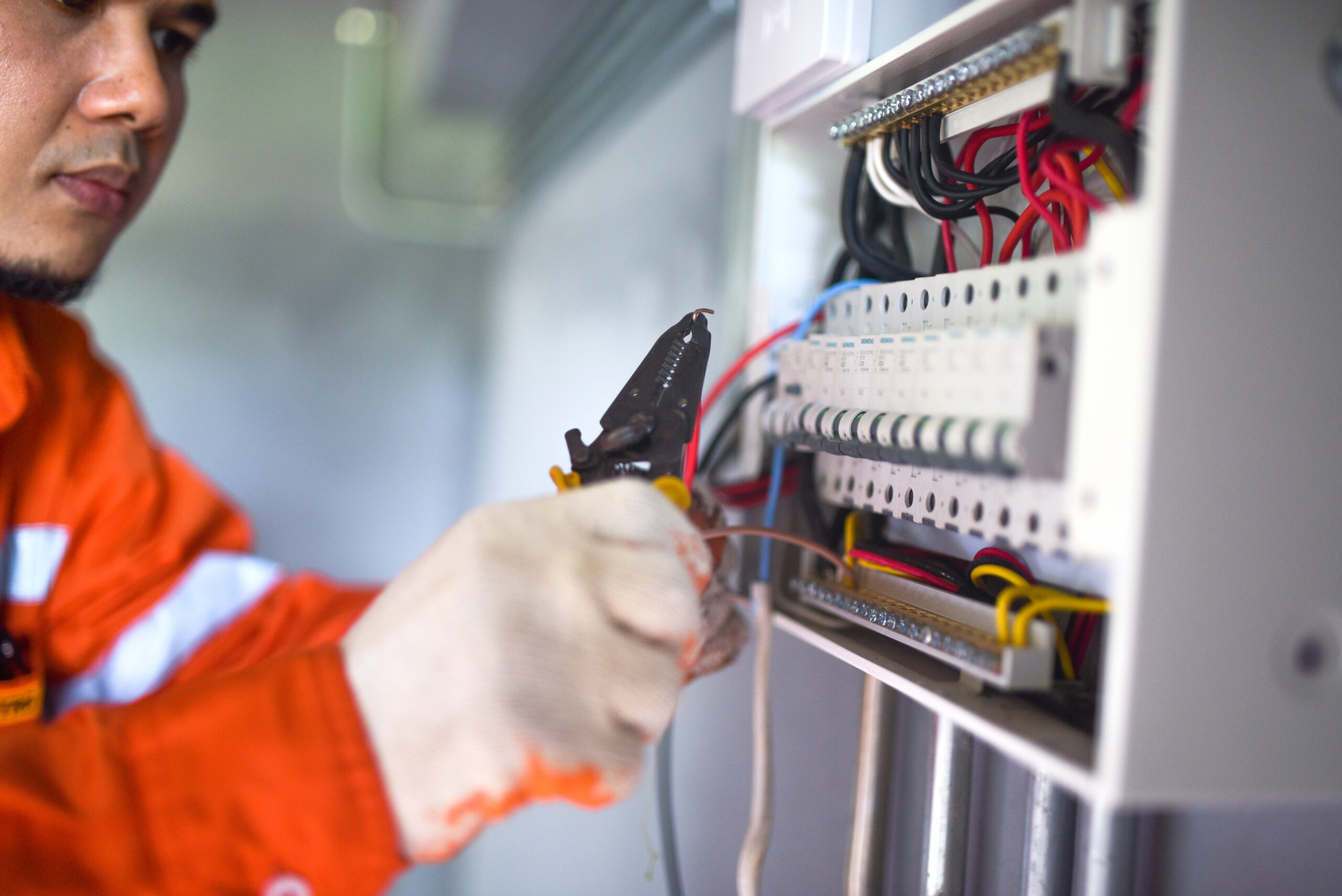 Главная side view of a handsome asian electrician repairing an electrica